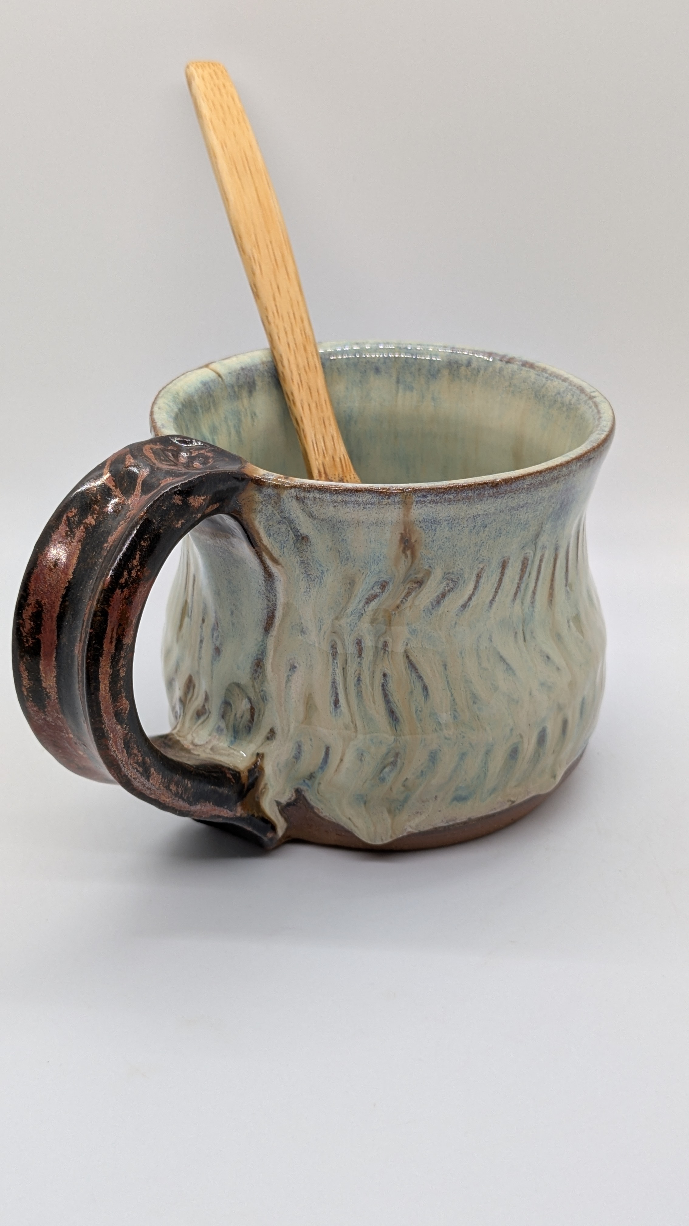 Turquoise Flux Mug - A rich, ivory color is accented by perfect drips of soft blues, grays, and browns running over a handcarved texture, and offset by a copper-toned handle with thumb rest. This mug holds about 10 oz. of your favorite tea or coffee. - 35